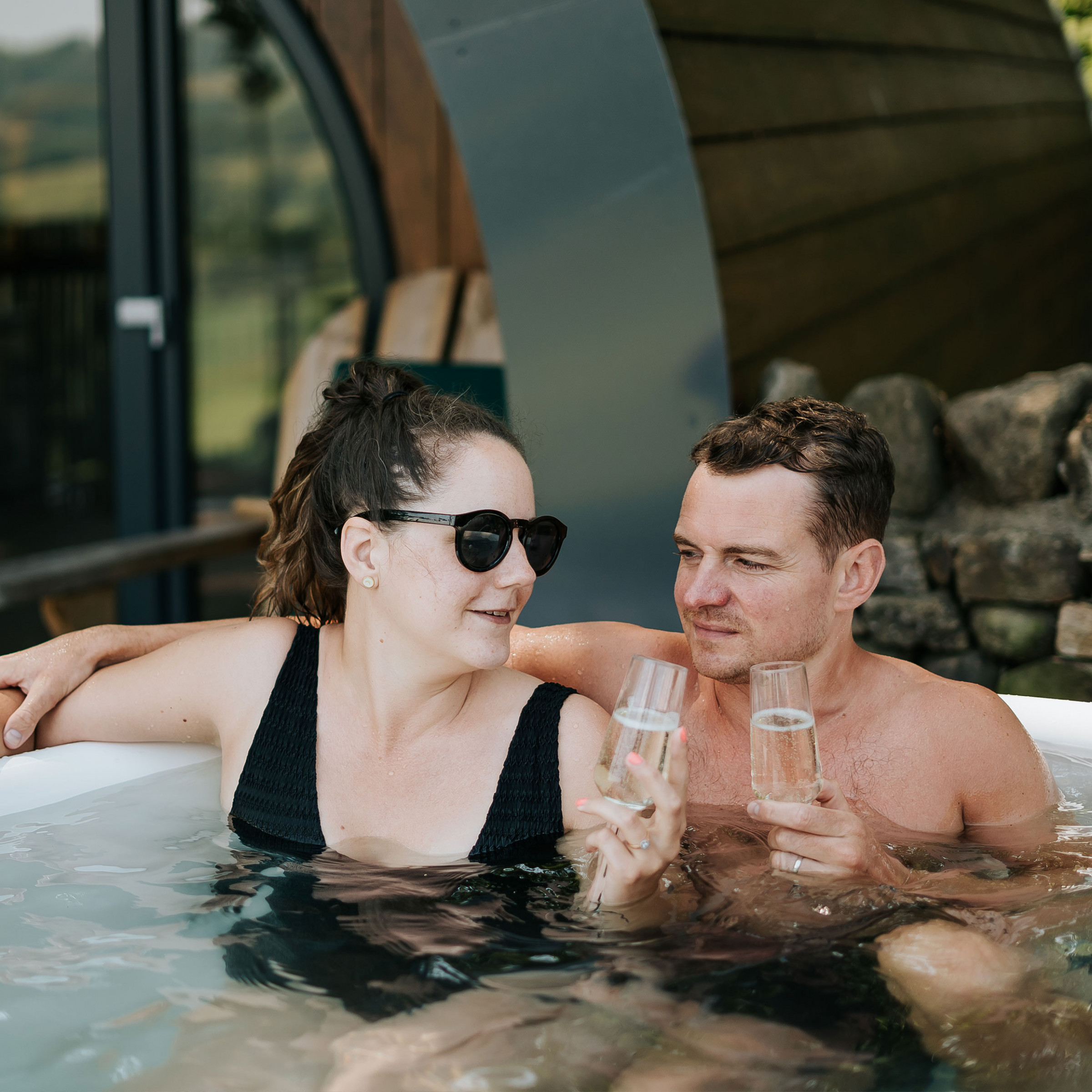 A couple relaxing together in the hot tub at Catgill Farm under the stars.