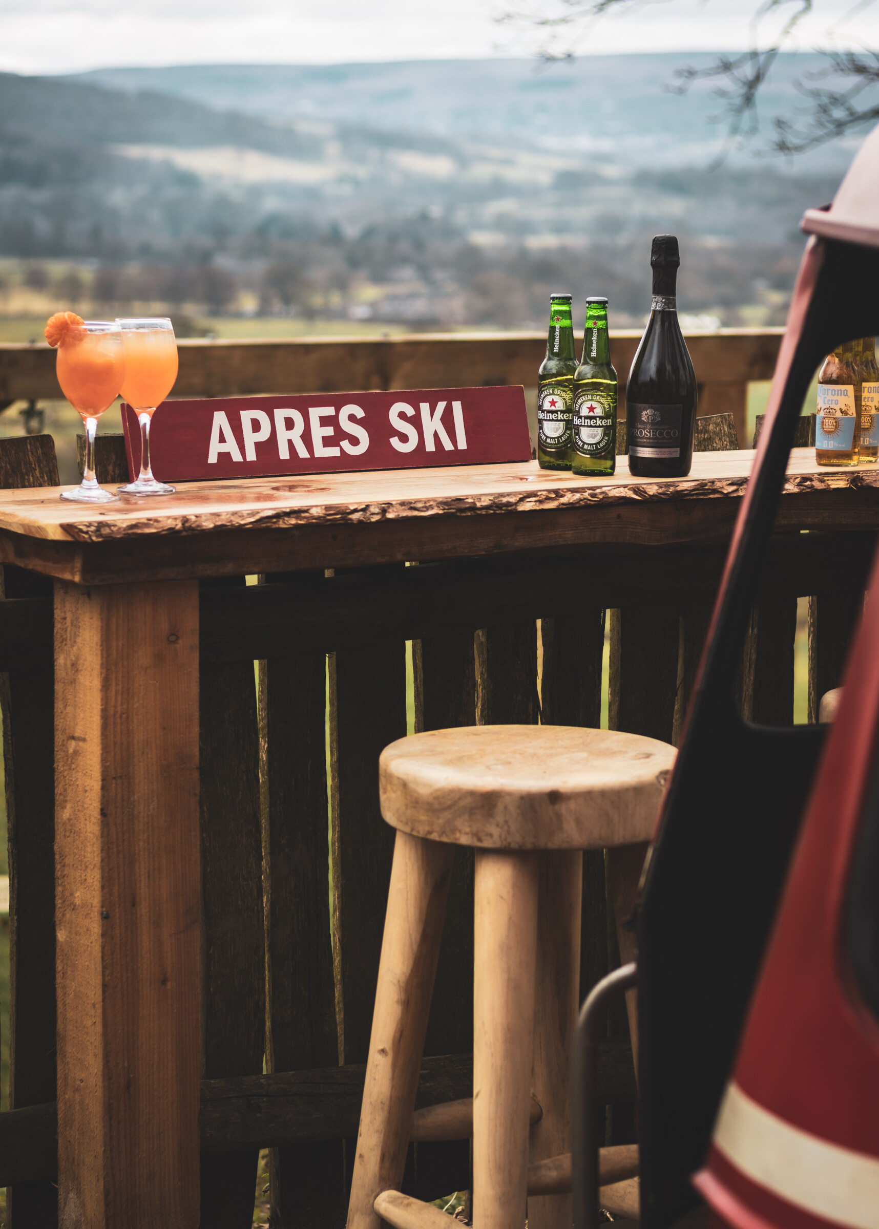 Après-ski bar with drinks and gondola chair on the patio of the Swiss Ski Station Pod, set against a scenic countryside backdrop.